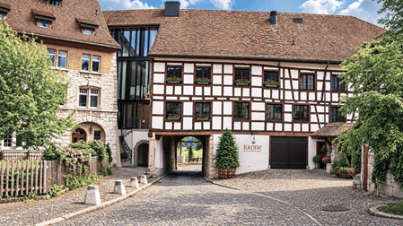 Historisches Fachwerkhaus mit Durchgang unter dem Gebäude in der Altstadt von Regensberg, umgeben von gepflasterten Gassen, traditionellen Ziegeldächern und liebevoll bepflanzten Gärten.